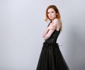 Beautiful elegant young model with bright redhead hairstyle posing in fashion chic black wedding dress with long skirt on studio