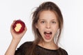 Beautiful emotional eight-year-old girl with an apple. Photo session in the studio. The girl is wearing a black blouse