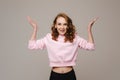 A beautiful emotional girl raises her hands up from happiness and what she sees on a gray background Royalty Free Stock Photo