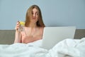 Beautiful emotional woman sitting in bed using laptop computer Royalty Free Stock Photo