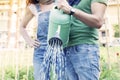 Beautiful engaged couple watering plants in the garden