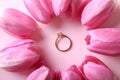 Beautiful engagement ring with tulips on color background, flat lay