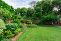 Beautiful English cottage garden, colorful flowering plant on smooth green grass lawn with orange brick wall Royalty Free Stock Photo