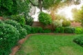 Beautiful English cottage garden, colorful flowering plant on smooth green grass lawn with orange brick wall
