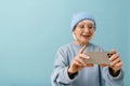 Beautiful enthusiastic senior woman holding phone looking on the screen