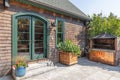 Beautiful entrance of a cozy mansion with an outdoor grill and potted plants Royalty Free Stock Photo