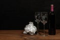 Beautiful etched wine glasses and bottle of red wine and white roses on wooden table and dark background Royalty Free Stock Photo