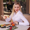 Beautiful european girl having sushi roll, holding sushi with chopsticks Royalty Free Stock Photo