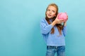 Beautiful european girl holding a piggy bank in her hands on a light blue background Royalty Free Stock Photo