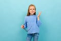 Beautiful european girl squints with glasses in hand on light blue wall