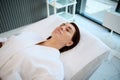 Beautiful European middle aged woman with perfect glowing skin lying down on a massage table in a spa room, relaxing while Royalty Free Stock Photo