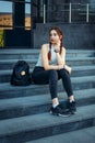 Beautiful European student with a backpack sitting on the steps near the University, close-up. A young pretty student in jeans