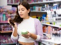 Beautiful european woman buying shampoo or hair care products in supermarket Royalty Free Stock Photo