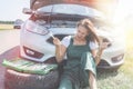 Beautiful European woman repairs the car on the road