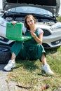 Beautiful European woman repairs the car on the road