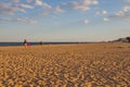 Beautiful evening beach. Shadows fall on the sand. Young mother with a child walk near the sea