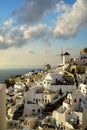 Beautiful evening light scene of Oia white building townscape along island mountain, Aegean sea, abstract cloud and blue sky