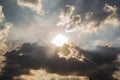 Beautiful evening skyscape. Sun`s rays shine through hole in black clouds before rain, natural background Royalty Free Stock Photo