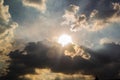 Beautiful evening skyscape. Sun`s rays shine through hole in black clouds before rain, natural background Royalty Free Stock Photo