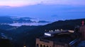 The sunset behind the mountains of Taiwan creates a purple backdrop against clear skies at dusk.