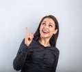 Beautiful excited business woman in black t-shirt pointing the finger up with toothy smiling on empty copy space blue studio Royalty Free Stock Photo