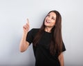 Beautiful excited casual woman in black t-shirt pointing the finger up with toothy smiling on empty copy space. Closeup Royalty Free Stock Photo