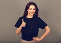 Beautiful excited energetic smiling casual woman showing finger thumb up by hand, the ok sign in blacl shirt on grey light studio Royalty Free Stock Photo