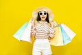 Beautiful excited happy young shopaholic asian woman wearing sungalsses and floppy hat posing isolated over yellow background Royalty Free Stock Photo