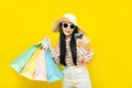 Beautiful excited happy young shopaholic asian woman wearing sungalsses and floppy hat posing isolated over yellow background Royalty Free Stock Photo