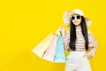 Beautiful excited happy young shopaholic asian woman wearing sungalsses and floppy hat posing isolated over yellow background Royalty Free Stock Photo