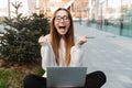 Beautiful excited shocked young happy business woman posing sitting outdoors near business center wearing eyeglasses using laptop Royalty Free Stock Photo