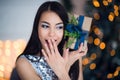 Beautiful excited smiling young woman with present gift feeling happy near christmas tree. Close-up portrait Royalty Free Stock Photo