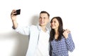 Beautiful excited young straight couple making funny faces, laughing, smiling & taking selfie, having fun w/ mobile cell phone cam Royalty Free Stock Photo