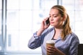 Beautiful executive listening to cellphone with coffee at creative office Royalty Free Stock Photo