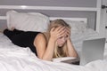 Beautiful exhausted blonde with laptop on bed with white sheets. pretty people at isolation