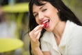 Beautiful exited woman eating strawberry lunch out of office on city street on public place. Royalty Free Stock Photo
