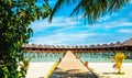 Beautiful exotic beach and wooden bridge to amazing exotic bungalows on turquoise water Royalty Free Stock Photo