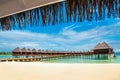 Beautiful exotic beach and wooden bridge to amazing exotic bungalows on turquoise water Royalty Free Stock Photo