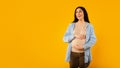 Beautiful expectant woman touching belly, looking aside at free space and smiling, panorama