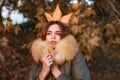 Beautiful exquisite girl standing in the park freezing in a jacket with fur. Autumn queen. Fall season outfit. Modern Royalty Free Stock Photo