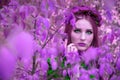 A beautiful and fabulous girl in a purple foliage with red wreath