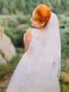 Beautiful fabulous happy redhair bride looking over shoulder on background of Carpathians mountains