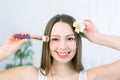 Beautiful face of young adult woman with clean fresh skin holding makeup brush in one hand and the flower in another Royalty Free Stock Photo