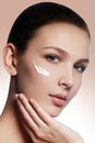 Beautiful face of young woman with cosmetic cream on a cheek. Sk Royalty Free Stock Photo