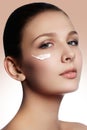 Beautiful face of young woman with cosmetic cream on a cheek. Sk Royalty Free Stock Photo