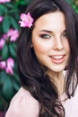 Beautiful face of young woman with makeup over the pink flowers. Portrait of the pretty healthy skin girl.Outdoor