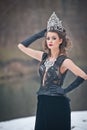 Beautiful fairy-tale winter queen in the forest with sparkling tiara and Elegant black fur coat.