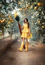 Beautiful fairytale fantasy woman holding large brown paintbrush yellow paint in hands. Girl in short dress rubber boots