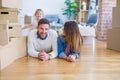 Beautiful famiily with kid lying down at new home around cardboard boxes