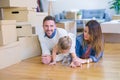 Beautiful famiily with kid lying down at new home around cardboard boxes